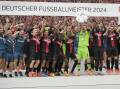 Leverkusen goalkeeper Lukas Hradecky hoists the Bundesliga trophy surrounded by teammates. (AP PHOTO)